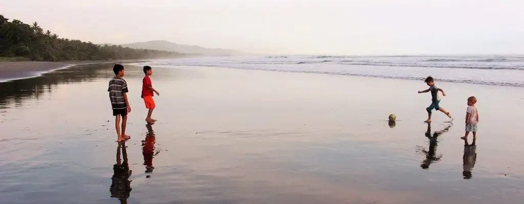 Weiße Bauhaus-Bungalows unter Kokospalmen am einsamen Strand von West-Bali: Hier haben wir den kleinen Clive kennen gelernt! Er hat das Glück hier aufzuwachsen… mit Strand, Palmen, Sonne, Mama, Papa, Oma und Opa, einheimischen Kids und Besucherkindern …